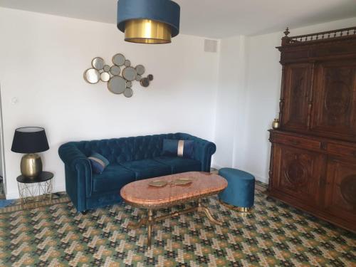 a living room with a blue couch and a table at Parfum de liberté in Le Bosc