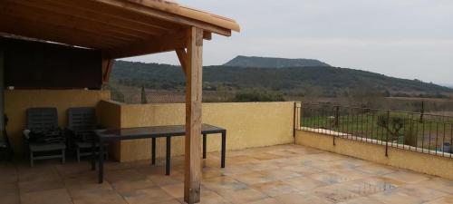 a patio with a table and chairs on a balcony at Parfum de liberté in Le Bosc