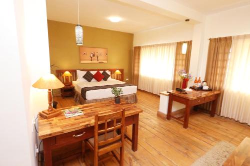 a bedroom with a bed and a desk and a table at Destiny - The Farm Resort in Ooty