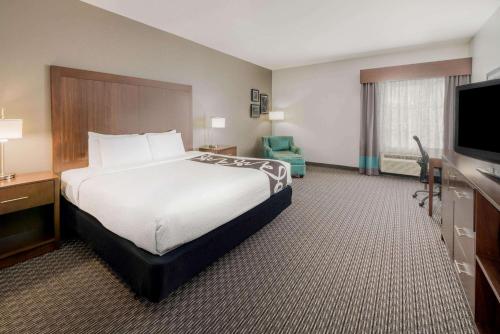 a hotel room with a bed and a flat screen tv at La Quinta Inn & Suites by Wyndham Fort Worth Arlington West in Arlington