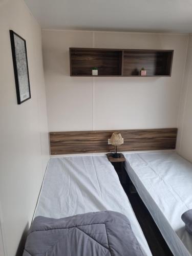 a bedroom with two beds and a lamp in it at Mobilhome des sables in Valras-Plage