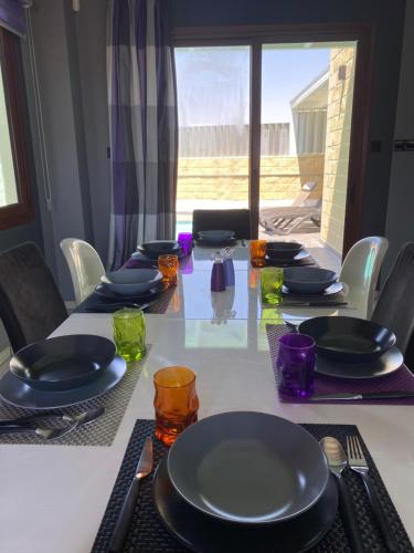 a table with plates and glasses on top of it at Purple Villa in Paralimni