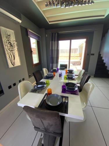 a dining room with a white table and chairs at Purple Villa Protaras - Paralimni in Paralimni