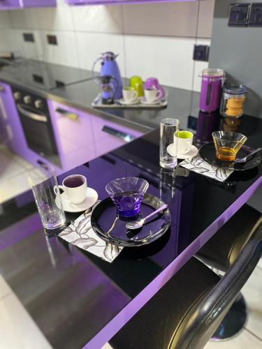 a purple counter top with plates and cups and glasses at Purple Villa Protaras - Paralimni in Paralimni