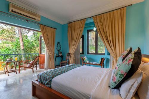 a bedroom with a bed with blue walls and a balcony at StayVista at Waterlily with Free Breakfast & Pvt Pool in Arpora
