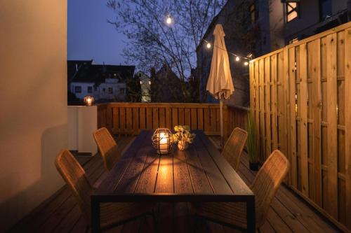 una mesa de madera con sillas en una terraza por la noche en Bheaven I Jugendstil Premium Apartment, en Bremerhaven