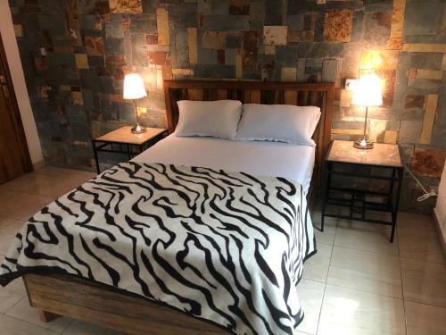 1 dormitorio con 1 cama con estampado de cebra y 2 mesas en A&H Villa, en Accra