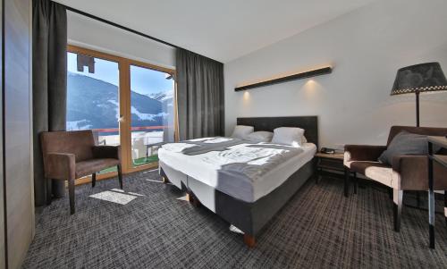 pokój hotelowy z łóżkiem, biurkiem i krzesłami w obiekcie Panoramahotel Fliesserhof w mieście Fliess