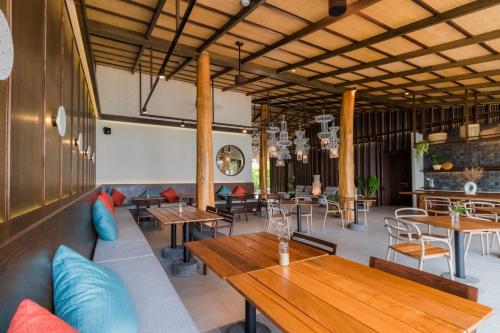 a restaurant with wooden tables and chairs in a room at The Flow Samui Beach Resort in Mae Nam