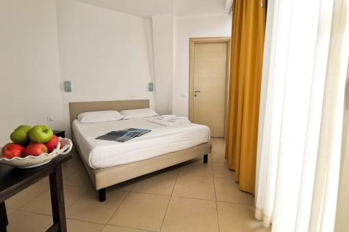 a bedroom with a bed and a bowl of fruit on a table at Hotel Poetto in Cagliari