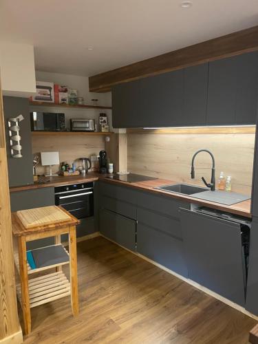 a kitchen with gray cabinets and a sink and a table at Maison Stabatio Appartement Margot in Le Monêtier-les-Bains