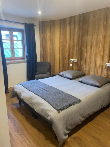 a bedroom with a large bed and a chair at Maison Stabatio Appartement Margot in Le Monêtier-les-Bains