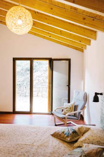 a bedroom with a chair and a large window at Quinta do Arade - Casa Girassol in Silves