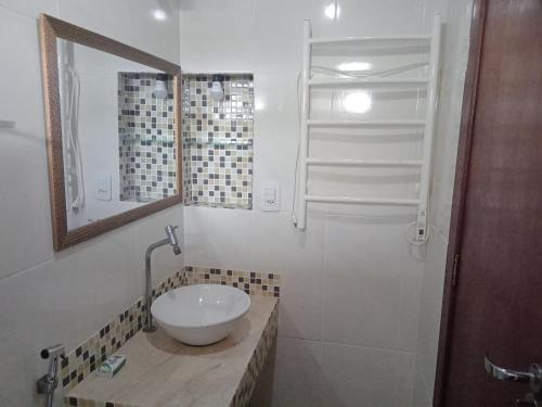 a bathroom with a sink and a mirror and a shower at Apts e suites em Stella Maris in Salvador