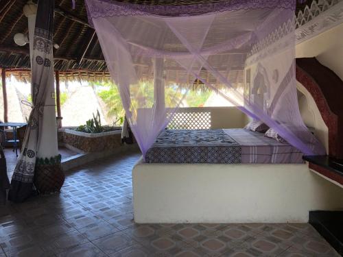 a bedroom with a bed with a mosquito net at Coconut Village Beach Resort in Diani Beach