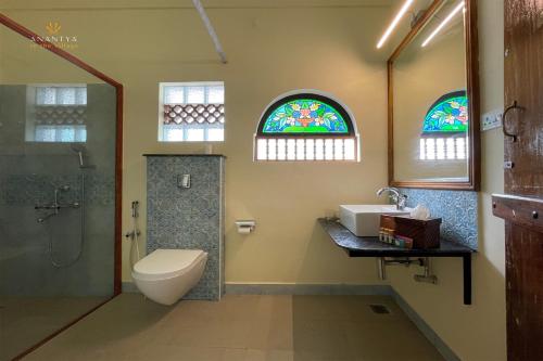 a bathroom with a toilet sink and stained glass windows at Anantya In The Village in Tuticorin