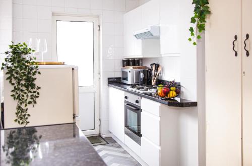 a kitchen with white cabinets and a white refrigerator at Contractor house, sleeps 5, close to restaurant's and bars, Long stays available, Oveyo Accommodation in Middlesbrough