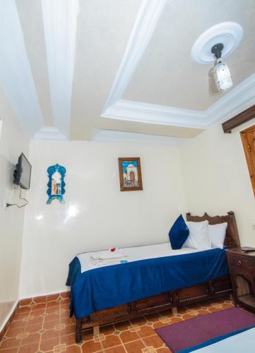 a bedroom with a bed with blue sheets and a ceiling at Hotel Al kassaba in Chefchaouene