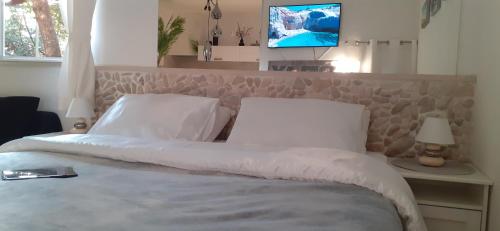 a bed with white pillows and a tv in a room at Relax tiny villas 40 meters of the beach in Korčula