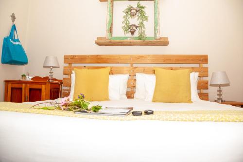 a bed with yellow pillows and flowers on it at De Akker Guest House Oudtshoorn in Oudtshoorn
