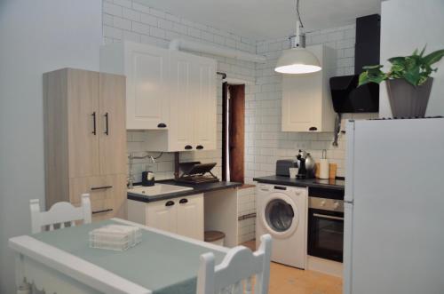 cocina con armarios blancos, lavadora y secadora en Apartamento Hiedra, en Santillana del Mar
