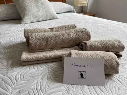- une pile de serviettes sur un lit avec un panneau dans l'établissement Albareda piso super-céntrico en Sarria, à Sarria