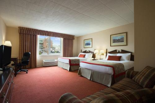 a hotel room with two beds and a couch at Ramada by Wyndham Ligonier in Ligonier
