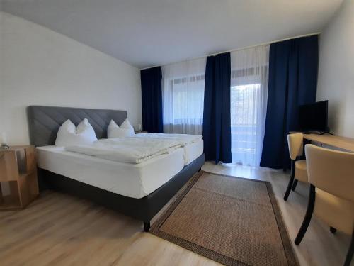 a bedroom with a large bed and a desk at Hotel Pension Blüchersruh in Bad Berneck im Fichtelgebirge