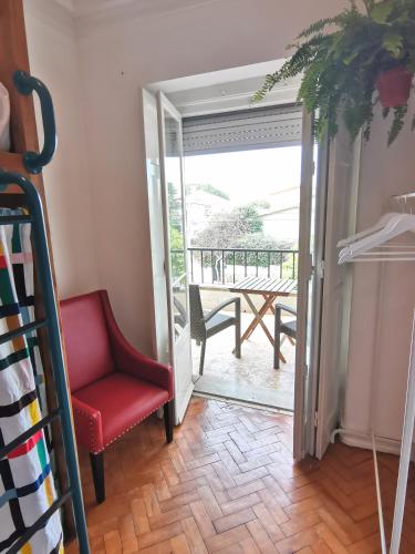 a room with a red chair and a balcony at Botanique Guesthouse in Cascais