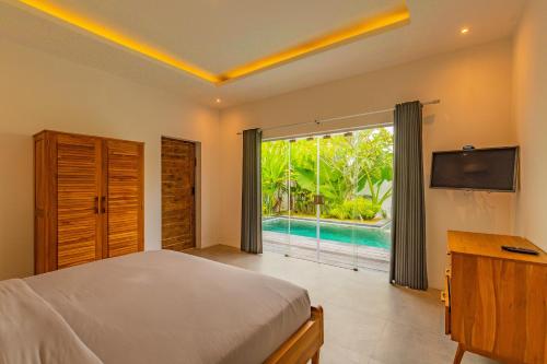 1 dormitorio con 1 cama, TV y piscina en Hedonia Luxury Villas, en Seminyak