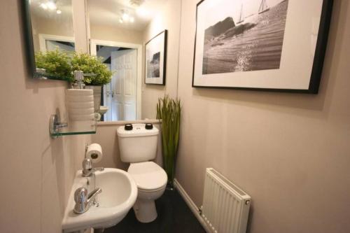a bathroom with a white toilet and a sink at Daimler House - Cosy Home Near Coventry City Centre in Coventry