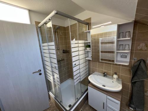 een badkamer met een glazen douche en een wastafel bij Strandnest Büsum Ferienhaus in Büsumer Deichhausen