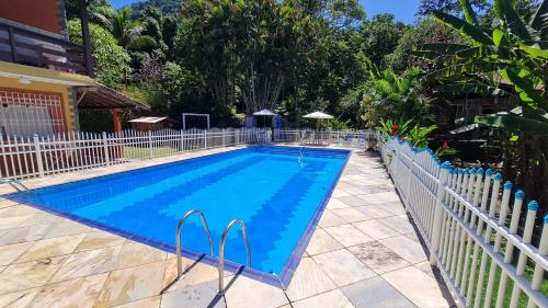 een zwembad met een wit hek eromheen bij Rancho Cravo e Canela - Guapimirim in Guapimirim