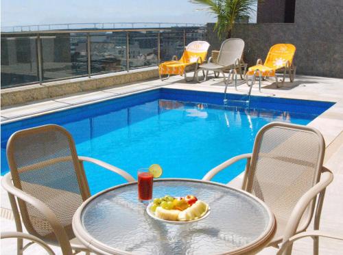 a table with a bowl of fruit on it next to a pool at Windsor Asturias Hotel in Rio de Janeiro
