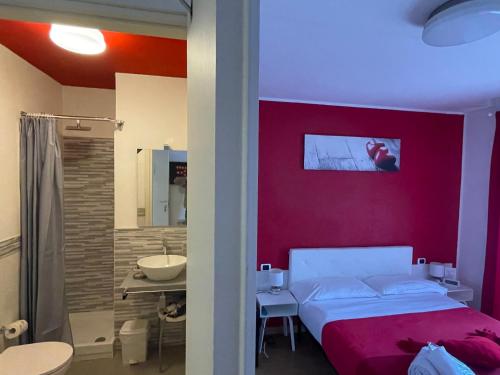 sypialnia z czerwoną ścianą z łóżkiem i łazienką w obiekcie AD Trastevere Guest House - by AD Roma w Rzymie