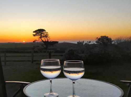 two glasses of wine sitting on a table with the sunset at Trevose, sea views in Port Isaac
