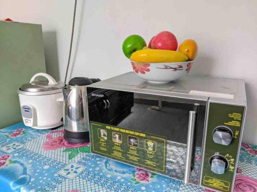 a bowl of fruit sitting on top of a microwave at HOMESTAY DELISHA PARIT RAJA UTHM in Parit Raja