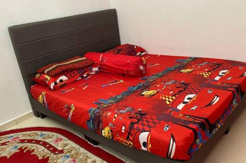 a bed with a red comforter and pillows on it at HOMESTAY DELISHA PARIT RAJA UTHM in Parit Raja