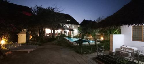 una casa con piscina en el patio por la noche en PWANI HOUSE cottage en Watamu