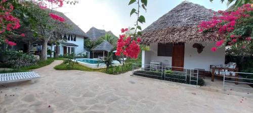a villa with a swimming pool and a house at PWANI HOUSE cottage in Watamu