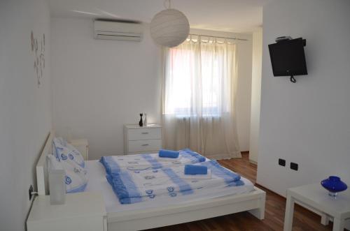 a bedroom with a bed with blue sheets and a television at Apartments Bertok in Koper