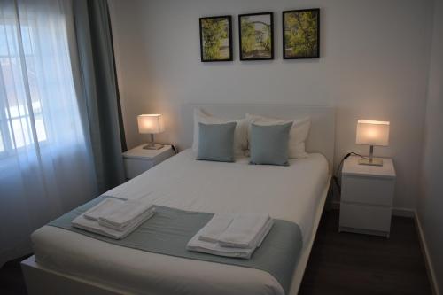 a bedroom with a large white bed with two lamps at Casa do Sapateiro in Ferrel