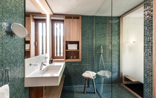 a bathroom with a sink and a shower with green tiles at La Paula Apartments & Suites in Siusi