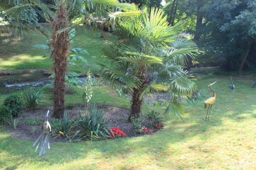 two birds standing in a garden with trees and flowers at Chambres d'Hôtes & Gites Pouget in Les Eyzies-de-Tayac