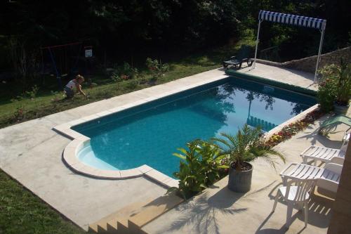 a swimming pool in a yard with chairs around it at Chambres d'Hôtes & Gites Pouget in Les Eyzies-de-Tayac