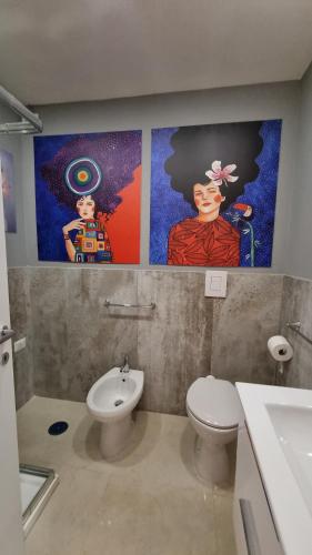 een badkamer met een toilet en twee schilderijen aan de muur bij FERDINANDO HOME in Caserta