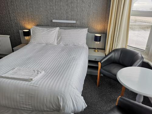 a bedroom with a bed and a chair and a table at Rockcliffe Hotel in Blackpool