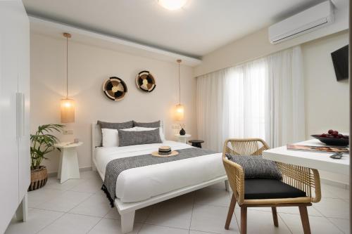 a white bedroom with a bed and a chair at Ormos Holiday Studios in Naxos Chora