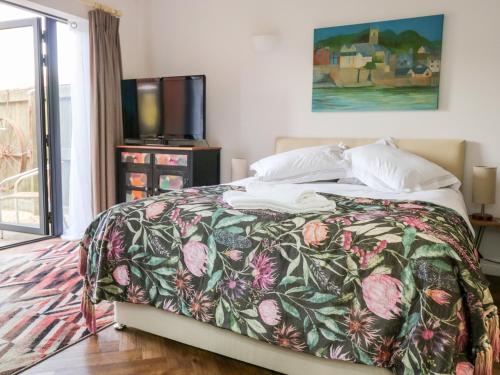 una camera da letto con un letto con un copriletto floreale e una TV di Farriers Retreat a Budleigh Salterton