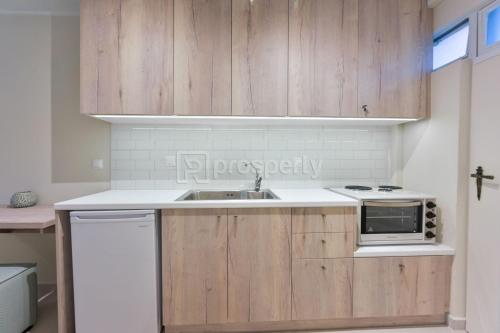 een keuken met houten kasten en een wastafel bij Sophia's studio in Saronida